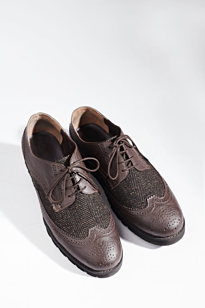 Close-up of stylish brown leather Oxford shoes with textured pattern on a clean white background.