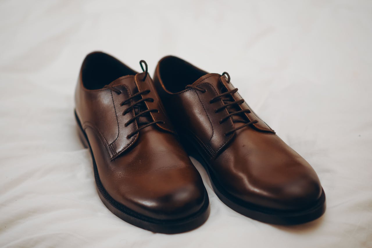 gallery-2 Pair of classic brown leather dress shoes resting on a white surface.