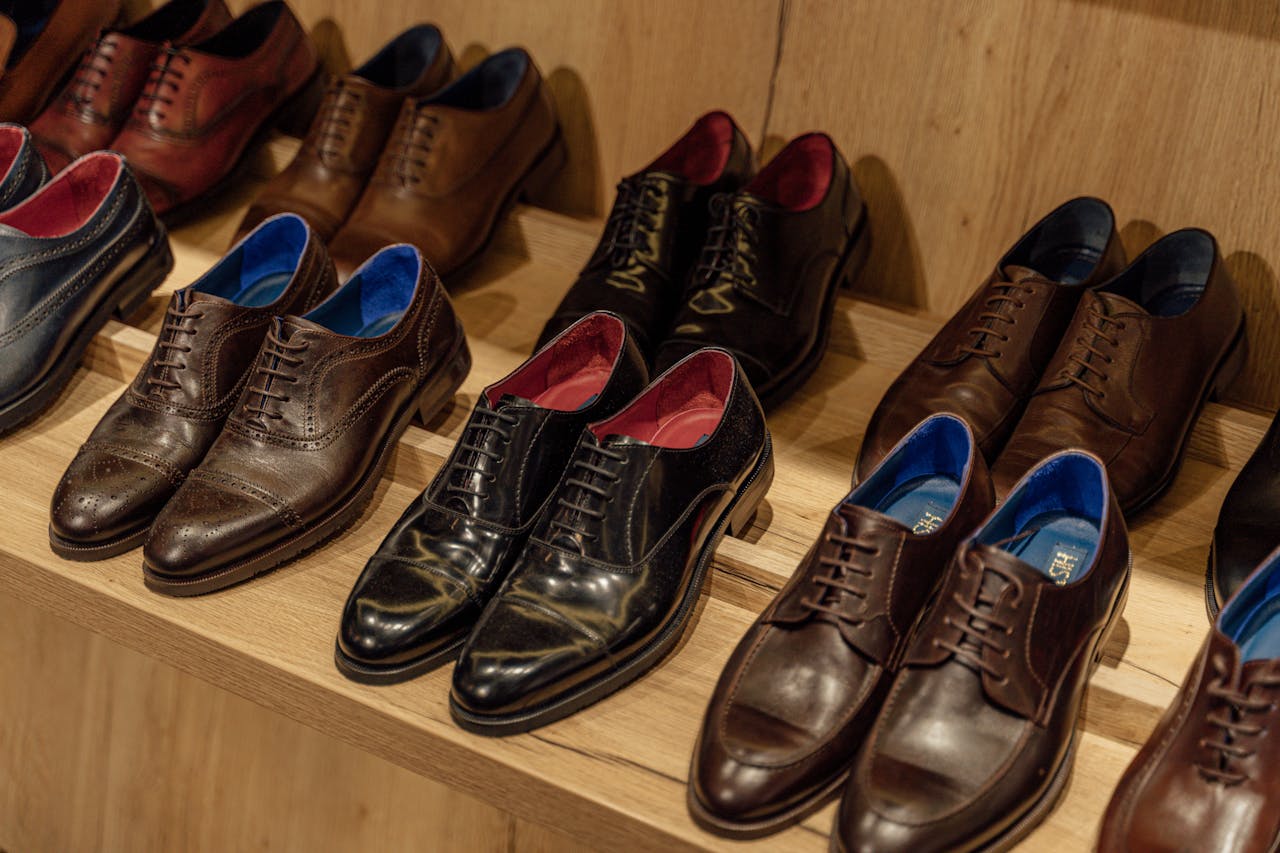 Showcase of elegant leather dress shoes on wooden shelves in-store display.