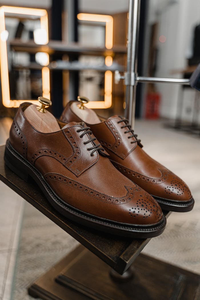contact-img Pair of classic brown leather brogue shoes showcased in a stylish setting.