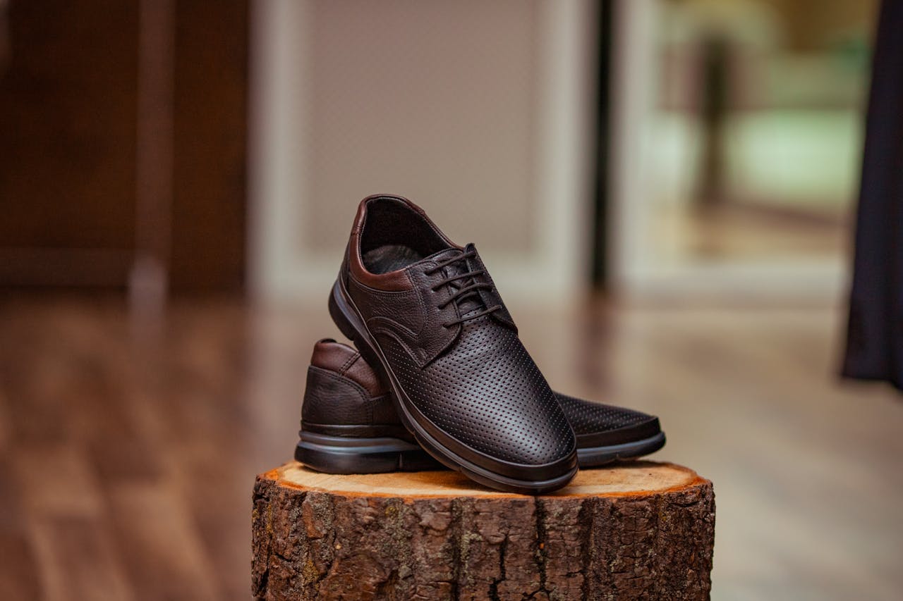 about-01 Stylish perforated leather shoes displayed elegantly on a rustic wooden stump indoors.